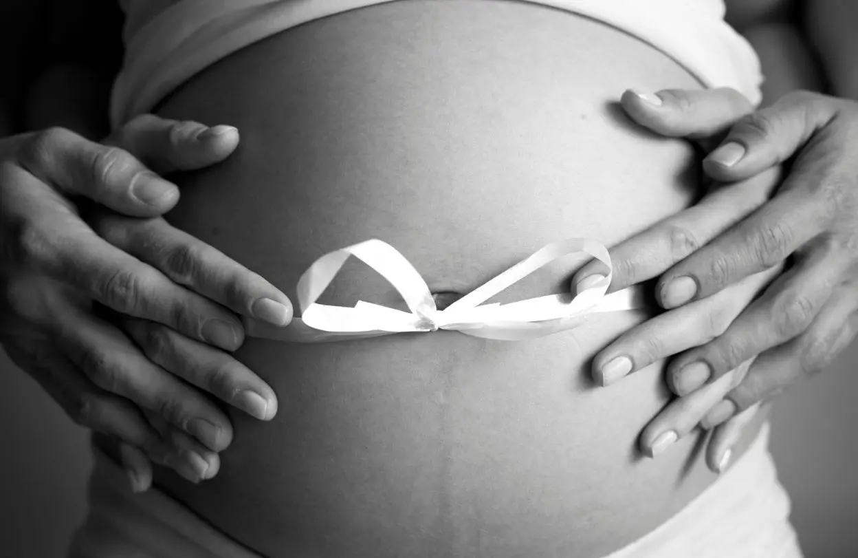 Photo noir et blanc d'un ventre de femme enceinte illustrant une séance de réflexologie périnatale à Saint Sébastien sur Loire